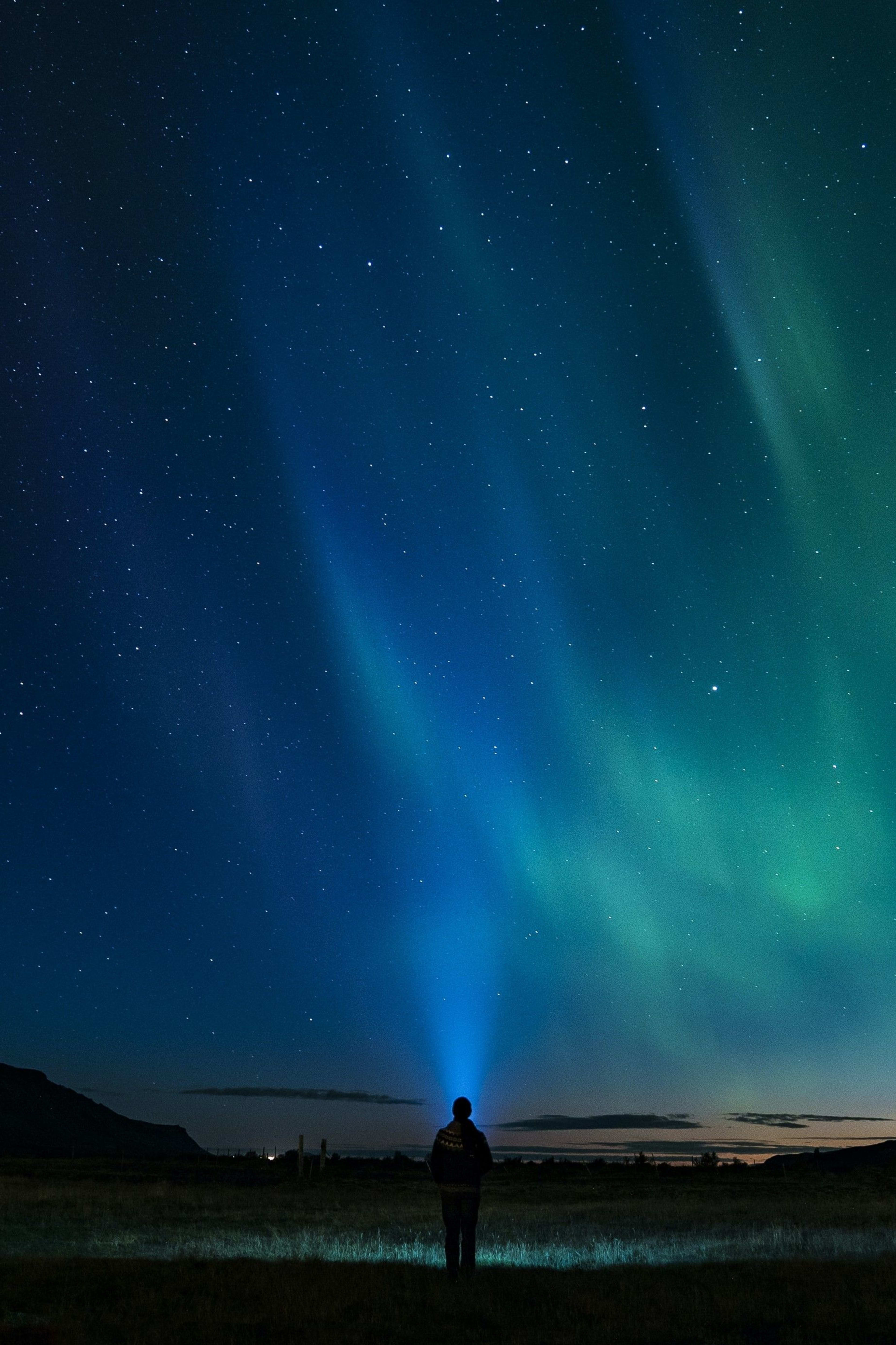 blue and green aurora with people standing